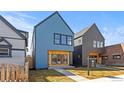 Stylish home showcasing a blue exterior, complemented by wood accents, dark framed windows, and a green lawn at 3725 N Franklin St, Denver, CO 80205