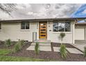 Inviting home exterior featuring a modern orange front door, fresh landscaping, and a newly painted exterior at 2076 S Yates St, Denver, CO 80219