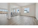 Bright and airy living room with large windows, gray wood flooring, and a view of the stairwell at 4975 Hickory Oaks St, Castle Rock, CO 80104