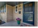 Close-up of the front door with secure entry, brick facade and colorful flower pot with flowers at 180 Dover St, Lakewood, CO 80226