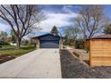 View of the detached garage, driveway, garden bed and backyard of this property at 180 Dover St, Lakewood, CO 80226