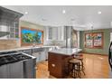 Bright, updated kitchen with stainless steel appliances, an island with seating, and hardwood floors at 8000 S Williams Way, Centennial, CO 80122