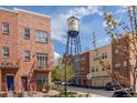 Brick townhomes with view of iconic Olde Town Arvada water tower on a sunny day at 7883 W 55Th Ave, Arvada, CO 80002