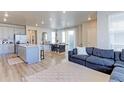 Bright living room with open floorplan features modern light fixtures, sliding glass door and wood floors at 5154 Bittercress Rd, Brighton, CO 80640