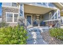 Charming covered porch with stone accents, seating, and landscaped entry to home at 1133 S Richfield St, Aurora, CO 80017