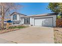 Well-manicured front yard with charming white brick facade, two-car garage, and classic black window trim at 16543 E Kansas Pl, Aurora, CO 80017