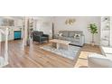 Bright living room with hardwood floors, a comfortable gray sofa, and view of a modern kitchen at 16543 E Kansas Pl, Aurora, CO 80017