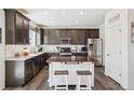 Modern kitchen featuring dark wood cabinets, stainless steel appliances, large island, and a pantry at 1846 Osprey Dr, Brighton, CO 80601