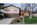 Inviting home exterior with brick accents, well-lit porch, and manicured front lawn with a large bare tree in the yard at 7290 Lamar Ct, Arvada, CO 80003