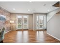 Bright living area with brick accent wall, hardwood floors, and double doors to the outside at 4108 W 118Th Pl, Westminster, CO 80031