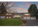 Charming red brick and white home with a well-manicured lawn, complemented by a neatly paved driveway at 930 Reed Ct, Lakewood, CO 80214