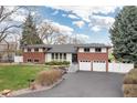 Charming red brick and white home with a well-manicured lawn, complemented by a neatly paved driveway at 930 Reed Ct, Lakewood, CO 80214