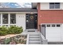 Up-close shot of the front entrance with a black door, stone steps, and freshly planted landscaping at 930 Reed Ct, Lakewood, CO 80214