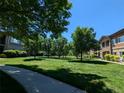 Lush, green community lawn lined with trees offers a park-like setting for residents at 1122 Olympia Ave # 12H, Longmont, CO 80504