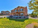 Charming two-story home with a well-manicured front lawn, complemented by vibrant flowering plants and lush greenery at 1235 Woodmoor Acres Dr, Monument, CO 80132