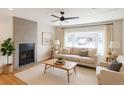 Bright living room featuring a tiled fireplace, ceiling fan, and large window at 8239 Nola Dr, Denver, CO 80221