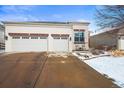 Stucco home featuring a spacious two-car garage and a welcoming front entrance with chairs on the porch at 6700 W Dorado Dr # 51, Littleton, CO 80123