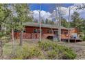 Cabin home with wood siding and a deck, surrounded by lush greenery and aspen trees at 26367 Pressler St, Conifer, CO 80433