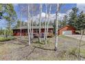 Cozy cabin-style house featuring a detached garage and surrounded by aspens and evergreens at 26367 Pressler St, Conifer, CO 80433
