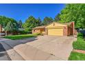 View of charming house on a tree lined street with a yellow garage door at 12348 Elizabeth Ct, Thornton, CO 80241