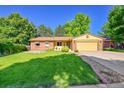 Charming brick and yellow home with a well-manicured lawn and mature trees at 12348 Elizabeth Ct, Thornton, CO 80241