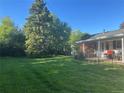 Large, grassy backyard featuring mature trees and a partially covered patio with outdoor seating at 3201 S Albion St, Denver, CO 80222