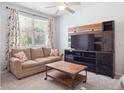 Cozy living room with a comfortable sofa, modern media center, and bright natural light streaming through the window at 3662 S Perth Cir # 104, Aurora, CO 80013
