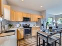 Well-lit kitchen featuring wood cabinetry, stainless steel appliances, and an eat-in dining table at 6065 Wadsworth Blvd # A, Arvada, CO 80003