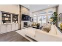 Elegant living room with a stone fireplace, built-in shelves, and large windows for natural light at 7214 S Shady Grove Ct, Aurora, CO 80016