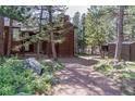 An outdoor shot showing the side of the home, a rock garden, and a gravel driveway through mature trees at 133 Mine Ln, Boulder, CO 80302