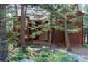 Exterior daytime shot shows a cozy wood home surrounded by trees and a stone pathway to the front door at 133 Mine Ln, Boulder, CO 80302