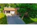 Aerial view of a brick home with attached garage, spacious driveway, and landscaped front yard at 2876 S Wolff St, Denver, CO 80236