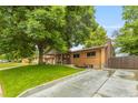Traditional brick home featuring a cozy front porch, mature tree, and driveway at 2876 S Wolff St, Denver, CO 80236