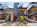 Modern townhome showcases a brick and metal exterior, complemented by a charming landscaped front yard at 9066 Harlan St, Westminster, CO 80031