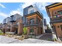 Contemporary townhome featuring brick and metal accents, a balcony, and a well-maintained landscaped front yard at 9066 Harlan St, Westminster, CO 80031