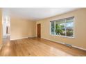 Bright living room featuring hardwood floors, a large window, and fresh paint, creating a welcoming space at 5502 E Center Ave, Denver, CO 80246