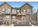 Multi-level townhome exhibits balcony, stone accents, red entry door, and xeriscaping at 18847 E Yale Cir # D, Aurora, CO 80013