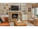 Living room featuring a stone fireplace, built-in shelving, and hardwood floors at 6941 S Poplar Way, Centennial, CO 80112