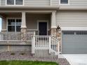 Inviting covered front porch with stone pillars and a gray door at 8807 Sedalia St, Commerce City, CO 80022