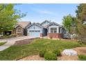 Beautiful blue home with green lawn, brick details, landscaped yard, and neighborhood view at 1118 S Duquesne Cir, Aurora, CO 80018