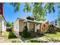 This bungalow-style home offers a welcoming front porch and is surrounded by mature trees and a green lawn at 284 S Lafayette St, Denver, CO 80209