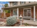 Inviting covered porch with brick detail, decorative shrubbery, and secure screen door at 8510 Independence Way, Arvada, CO 80005