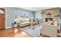 Cozy living room with a stone fireplace, hardwood floors, and a bright window at 3276 S Osceola St, Denver, CO 80236