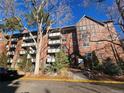 Brick condo building with balconies, mature trees, and professional landscaping at 1270 N Marion St # 103, Denver, CO 80218