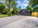 Spacious driveway leading to a well maintained house with an attached garage and mature trees at 3030 Alkire St, Golden, CO 80401