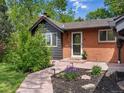 Inviting front entrance with a brick facade, a storm door, and beautiful landscaping at 3030 Alkire St, Golden, CO 80401