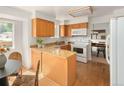 Well-lit kitchen with wood cabinets, granite countertops, modern appliances, and an adjacent dining area at 6463 S Vance St, Littleton, CO 80123
