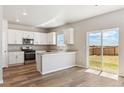 Bright eat-in kitchen featuring white cabinetry, stainless steel appliances, and sliding glass door to the backyard at 48255 Shetland Dr, Bennett, CO 80102