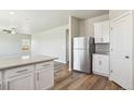 Open-concept kitchen with stainless steel refrigerator, white cabinetry, and a breakfast bar overlooking the living area at 48255 Shetland Dr, Bennett, CO 80102