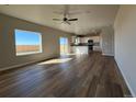 Open-concept living room featuring hardwood floors, a ceiling fan, and large windows at 48255 Shetland Dr, Bennett, CO 80102